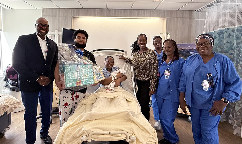 First-time parents Joannie Farris (center) and dad Robert Leandry (second, left) are pictured with their daughter Stella. Also pictured (from left): Edison Bond, Jr., MPH, MDiv, DMin, CPXP, Chief Patient Experience Officer, Jacqueline Marecheau, MD, FACOG, Chair of OBGYN, Sonnett Green, RN, Sandra Prendergast, RN, and Sufiya Abdin, Certified Surgical Technician at EHS.