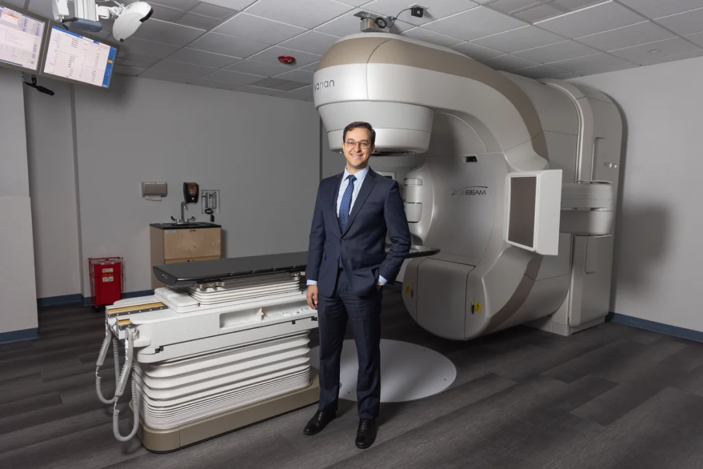 Photo of Dr. Ashamalla in front of the TrueBeam linear accelerator device.