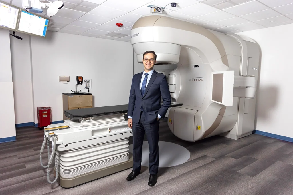 Photo of Dr. Ashamalla in front of the TrueBeam linear accelerator device.